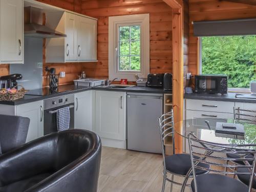 a kitchen with white cabinets and a table and chairs at Barken in Trawsfynydd