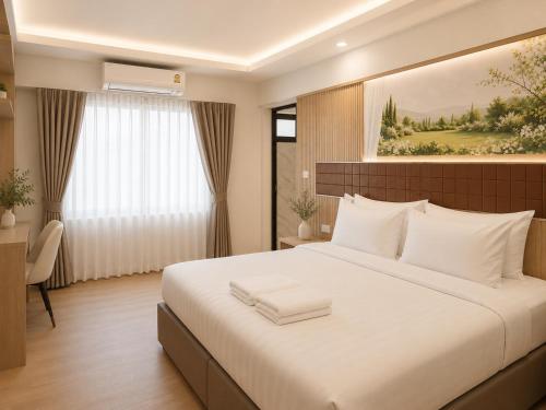 a bedroom with a large white bed and a window at Chanaplace Lanna in Chiang Mai