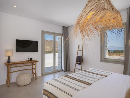a bedroom with a bed and a desk and a television at Villa Bema - Quietness and Beach access in Molos Parou