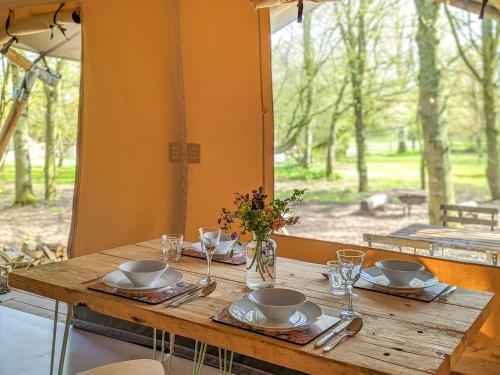 a wooden table with plates and dishes on it with a window at The Bushel - Ukc7131 in Cratfield
