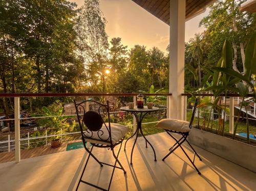 a porch with two chairs and a table on a balcony at Villa Leo in Ban Madua Wan