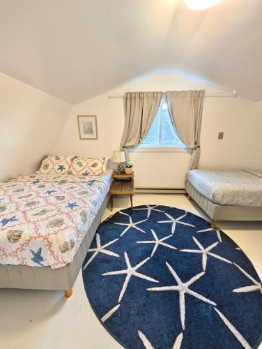 a bedroom with two beds and a blue rug at 2 Bed Rustic Retreat at Bois Joli Beach in Grand Barachois