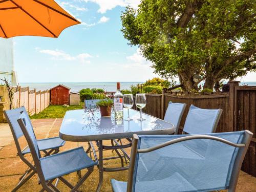 a table and chairs with wine glasses and an umbrella at Jan Dee Cottage in Ventnor