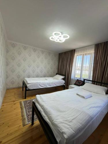 a bedroom with two beds and a window at Kamil Guest House in Shabdan