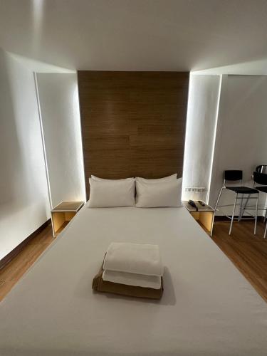 a bedroom with a large white bed with a wooden headboard at Love Box Resort in Samutprakarn