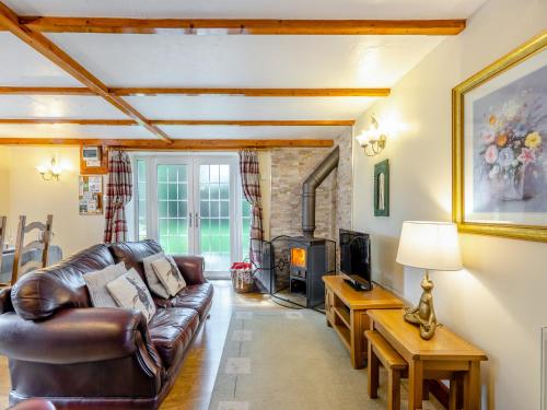 a living room with a leather couch and a fireplace at Lavender Cottage - Ukc6677 in Bettws-yn-Rhôs