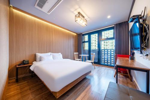 a bedroom with a large white bed and a desk at Benikea Hotel Kakao in Seoul
