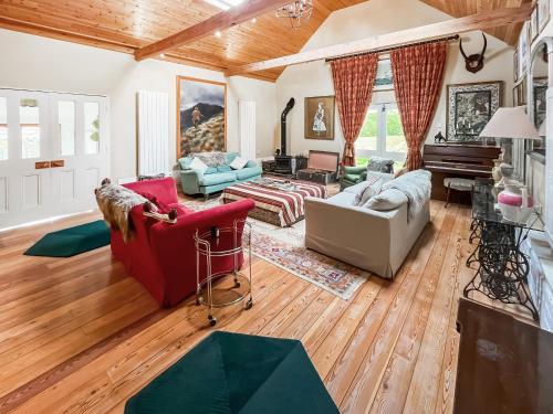 a living room filled with furniture and a piano at Munns Farm Barn in Earls Colne