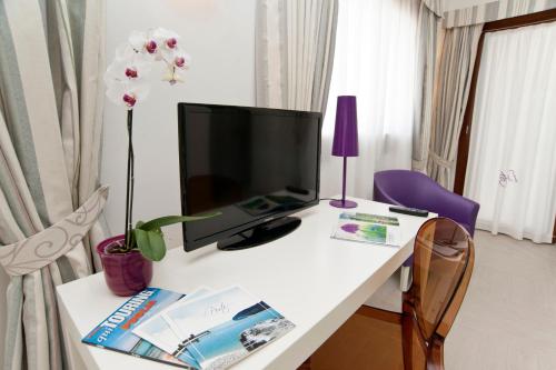 a white desk with a television and a purple chair at Hotel Residence Il Porto in Mattinata