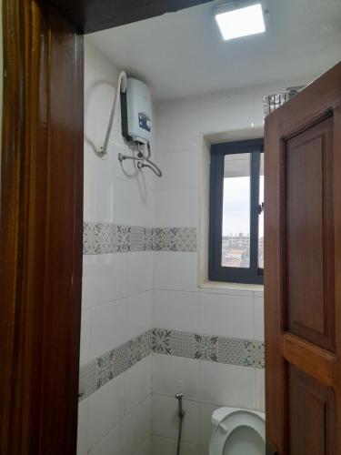 a bathroom with a toilet and a window at Ebenezer Apartment, Albert Cook Road in Kampala