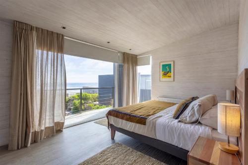a bedroom with a bed and a large window at Casas Punta Costanera in Pichilemu