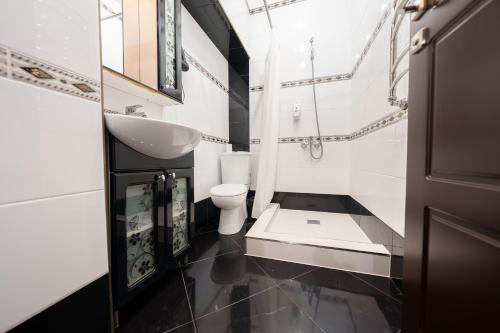 a white bathroom with a sink and a toilet at Pensiune Taviada in Chişinău