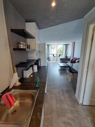 a kitchen with a sink and a living room at Sea View Calypso Condo in Mijas