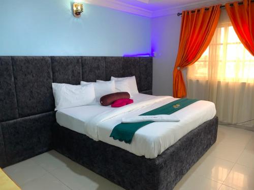 a bedroom with a large bed with red curtains at Diamond Groove Hotel & Suites in Sangotedo