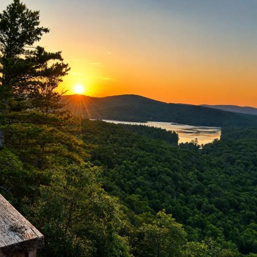 a sunset over a lake with a tree at White Mountains A-Frame Off-Grid Stars Firepit in North Lovell