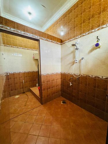 a bathroom with a shower in a tiled wall at Taman Darul Salam Homestay Pasir Puteh in Pasir Puteh