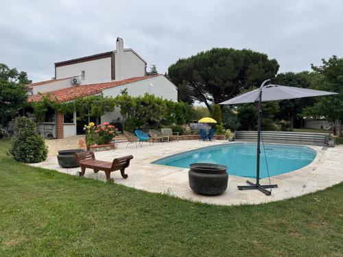 a swimming pool with an umbrella and a bench at Appartement à Tournefeuille in Tournefeuille