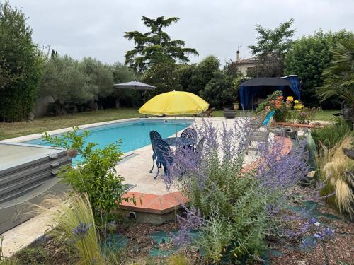 a swimming pool with a yellow umbrella and some flowers at Appartement à Tournefeuille in Tournefeuille