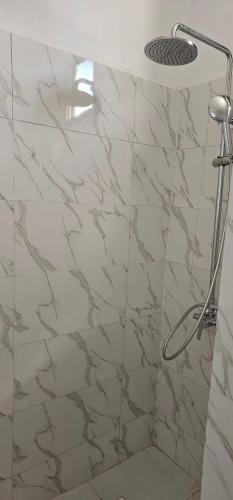 a shower in a bathroom with marble tiles at Nungwi Garden Boutique Hotel in Nungwi