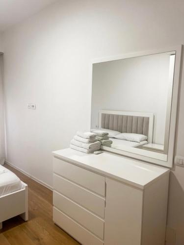a white room with a mirror and a white dresser at Shehu Apartments in Tirana
