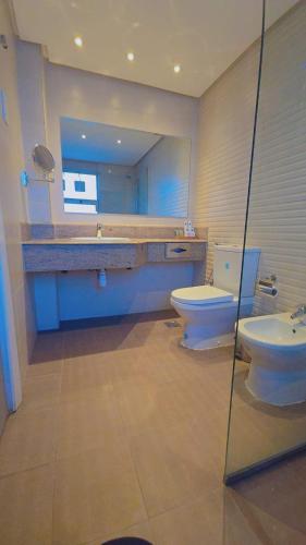 a bathroom with two toilets and a sink and a mirror at Mirador Hotel in Manama