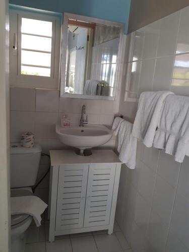 a white bathroom with a sink and a mirror at Marazul Apartment F1 in Sabana Westpunt