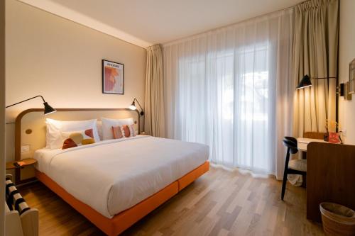 ein Hotelzimmer mit einem großen Bett und einem Fenster in der Unterkunft HOOD Hotel in Genf
