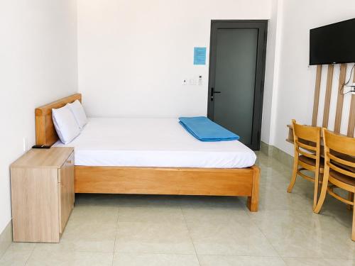 a bedroom with a bed and a tv and chairs at Khách sạn Đạt Tiến Quân in Ấp Bình Hưng