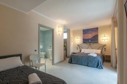 a bedroom with a bed and a chair and a mirror at Hotel Barcarola 2 in Marina di Campo
