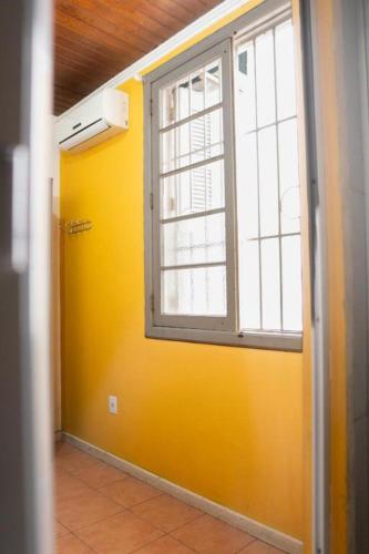 a room with a yellow wall and a window at POA Eco Hostel in Porto Alegre