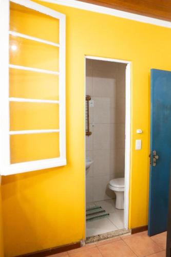 a bathroom with a yellow wall and a toilet at POA Eco Hostel in Porto Alegre