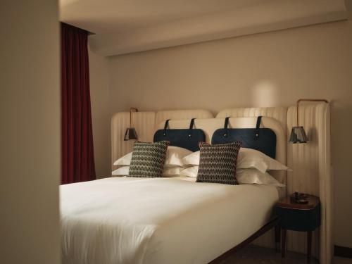 a large white bed with two pillows on it at The Shepherd Mayfair in London