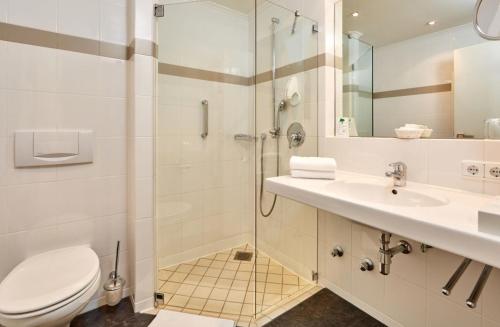a bathroom with a shower and a toilet and a sink at Hotel am Badersee in Grainau