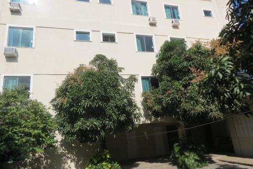 a white building with trees in front of it at Hotel Nanuque in Cabo Frio