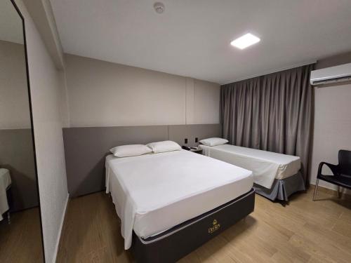 a hotel room with two beds and a chair at Village Iguassu Hotel in Foz do Iguaçu