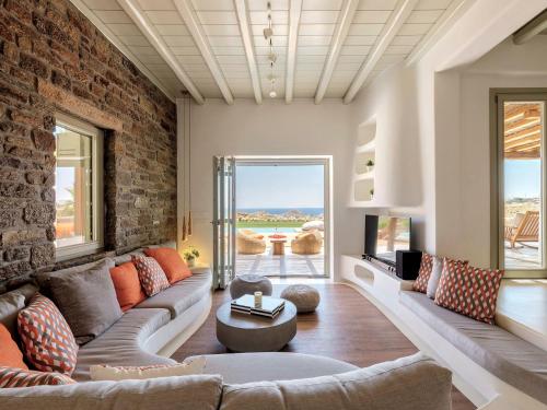 a living room with a couch and a brick wall at Villa Yasemin - Mykonos Paradise - Views - Pool - Large Garden in Kalafatis