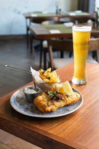 a plate of food on a table with a glass of beer at ONOMO Hotel Cape Town – Inn On The Square in Cape Town