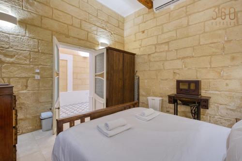 a bedroom with a white bed and a bathroom at Luqa Stone Maisonette Apartments Near Airport in Luqa