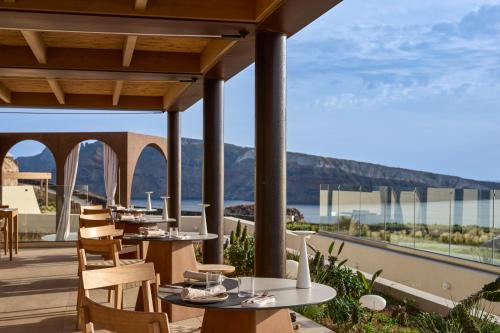 a restaurant with tables and chairs and a view of the ocean at Santo Mine Oia Suites in Oia