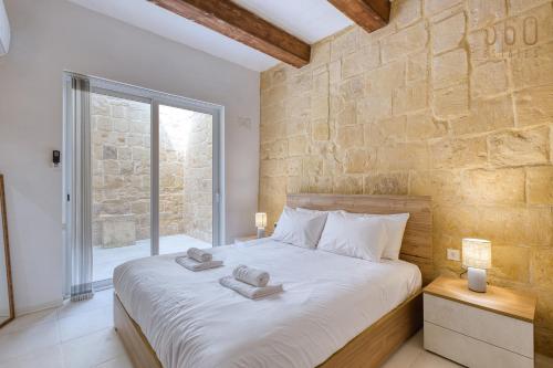 a bedroom with a large bed with towels on it at Luqa Stone Maisonette Apartments Near Airport in Luqa