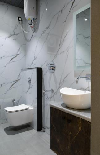 a bathroom with a sink and a toilet and a mirror at Dwarka Palace in Hingoli