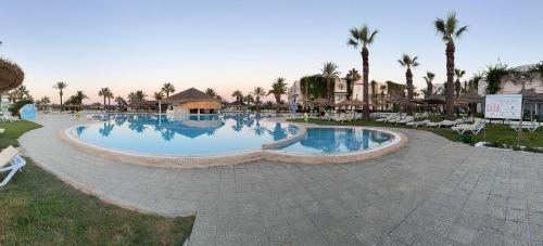 a large swimming pool at a resort with palm trees at Caribbean World Mahdia in Mahdia