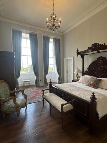 a large bedroom with a large bed and a chandelier at Uppercourt Manor in Freshford