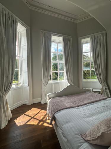 a bedroom with a bed and two windows at Uppercourt Manor in Freshford