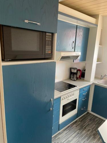 a small kitchen with blue cabinets and a microwave at FeWo Möwennest in Warnemünde