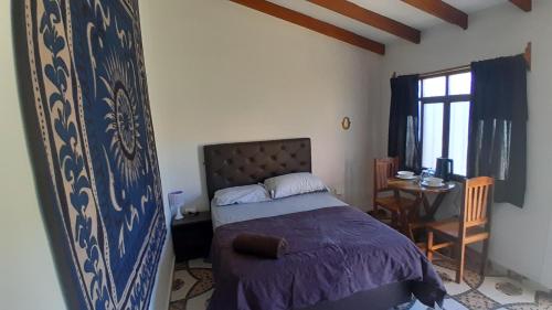 a bedroom with a bed and a table and a window at El Nido in Samaipata