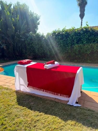 a red and white bed sitting next to a pool at Nikkita Wellness Spa in Pretoria