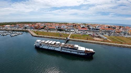 a cruise ship in the water next to a city at Costa do Sal Hotel Boat Lounge in Aveiro