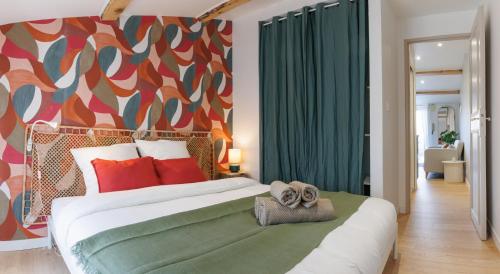 a bedroom with a large bed with a colorful wall at Le Cocon Perché - Centre Ville - Parking - Clim in Valence