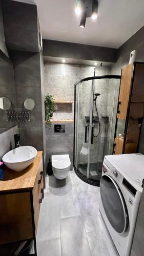 a bathroom with a shower and a sink and a washing machine at Loft No 35 Premium Apartment in Głogów